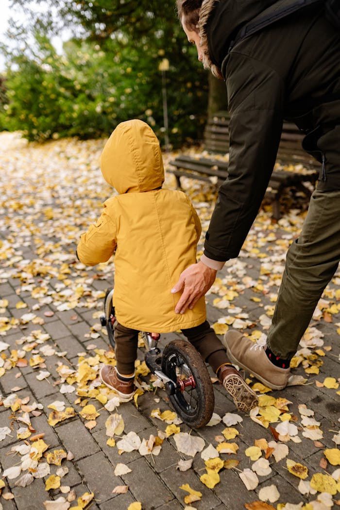 pexels-photo-6209934 A father and son enjoy a playful autumn day as they ride a bicycle in the park.
